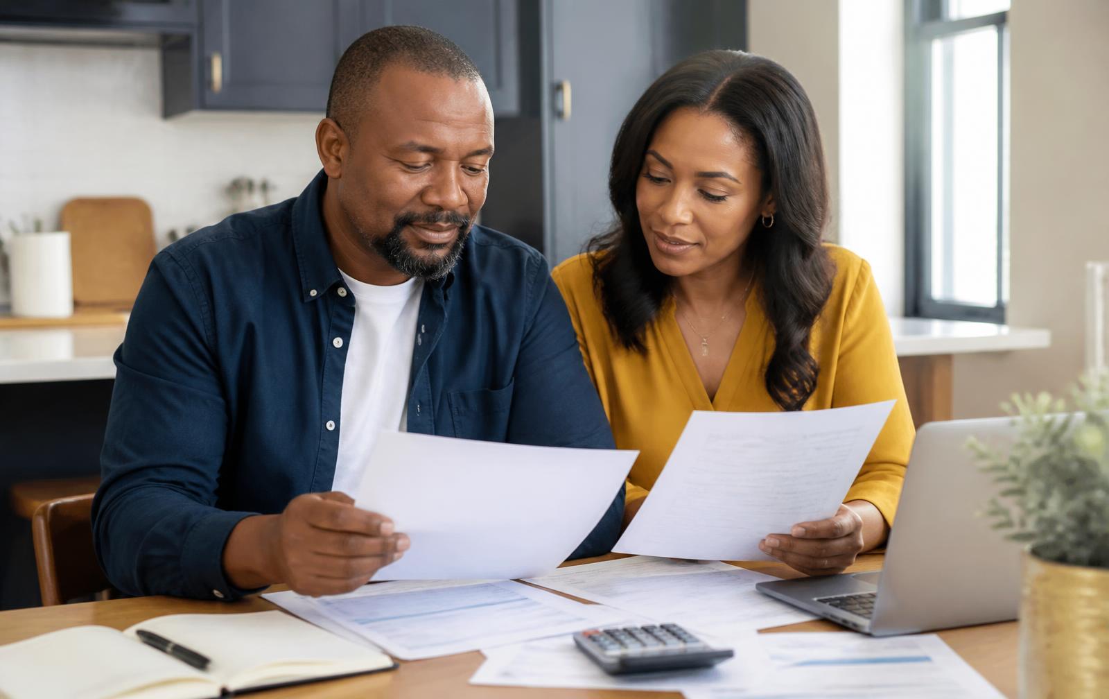 A couple reviewing financial paperwork together at their kitchen table